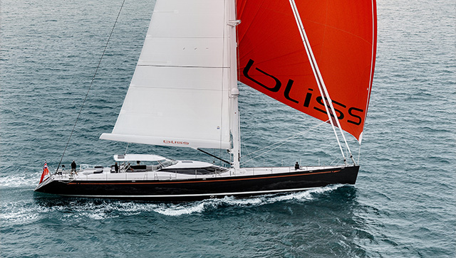 A sailing superyacht with red and white sails