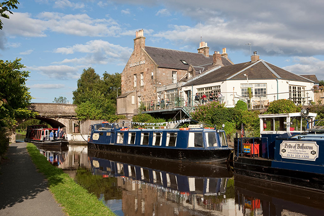 Narrowboat move along the canal past a pub in Edinburgh