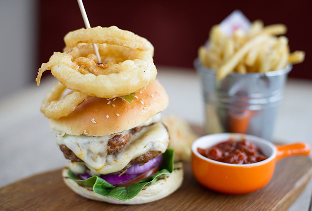 Burger with onion rings and a bowl of chilli