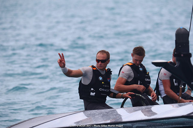 Jimmy Spithill dressed in grey and a black lifejacket