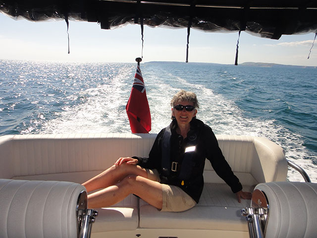 A lady wearing a life jacket enjoying a day out on a motor boat